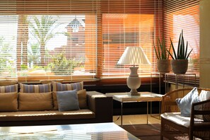 A living room with a sofa, a table, and a chair. There are potted plants on a side table. - Royal Hideaway Sancti Petri (Chiclana de la Frontera)