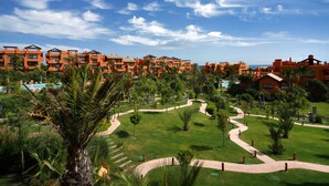 Ein Resort mit mehreren Gebäuden mit orangen Dächern, einem zentral gelegenen Pool und einem gepflegten Garten mit Wegen.