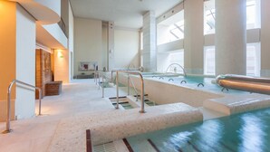 Ein Hallenbad mit großen Glaswänden, Fliesenboden und modernem Design.