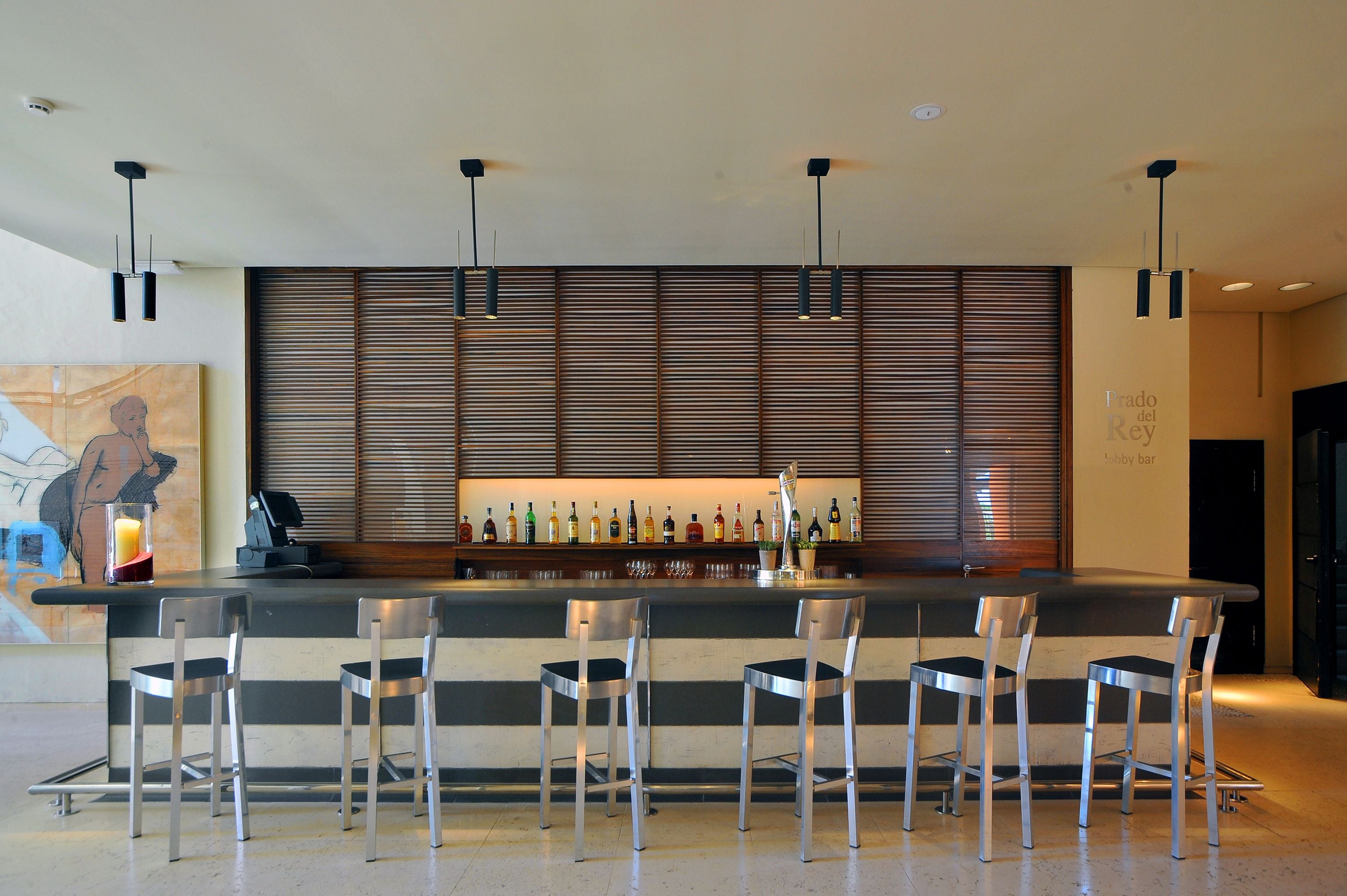 A bar area with a counter, bar stools, and a wall-mounted liquor display.