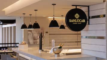 Eine moderne Bar mit Pendelleuchten, einer Bar und einem Schild mit der Aufschrift 'SANLUCAR LOBBY BAR'.