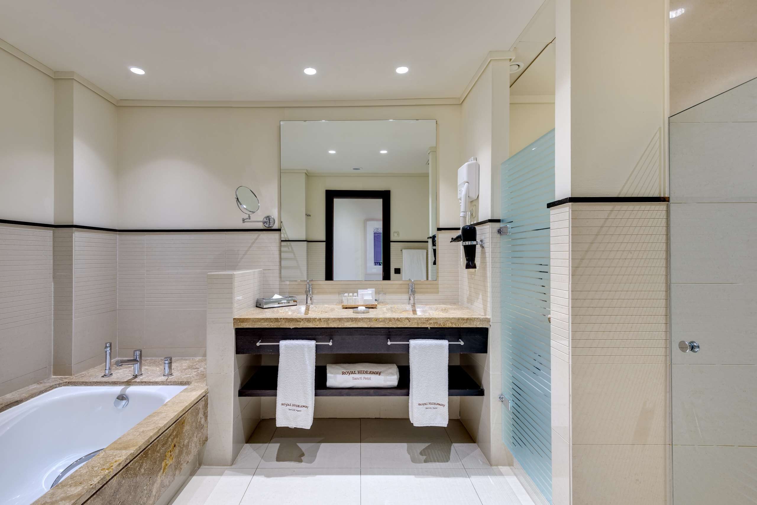 Un baño moderno con bañera, tocador doble y un espejo grande.