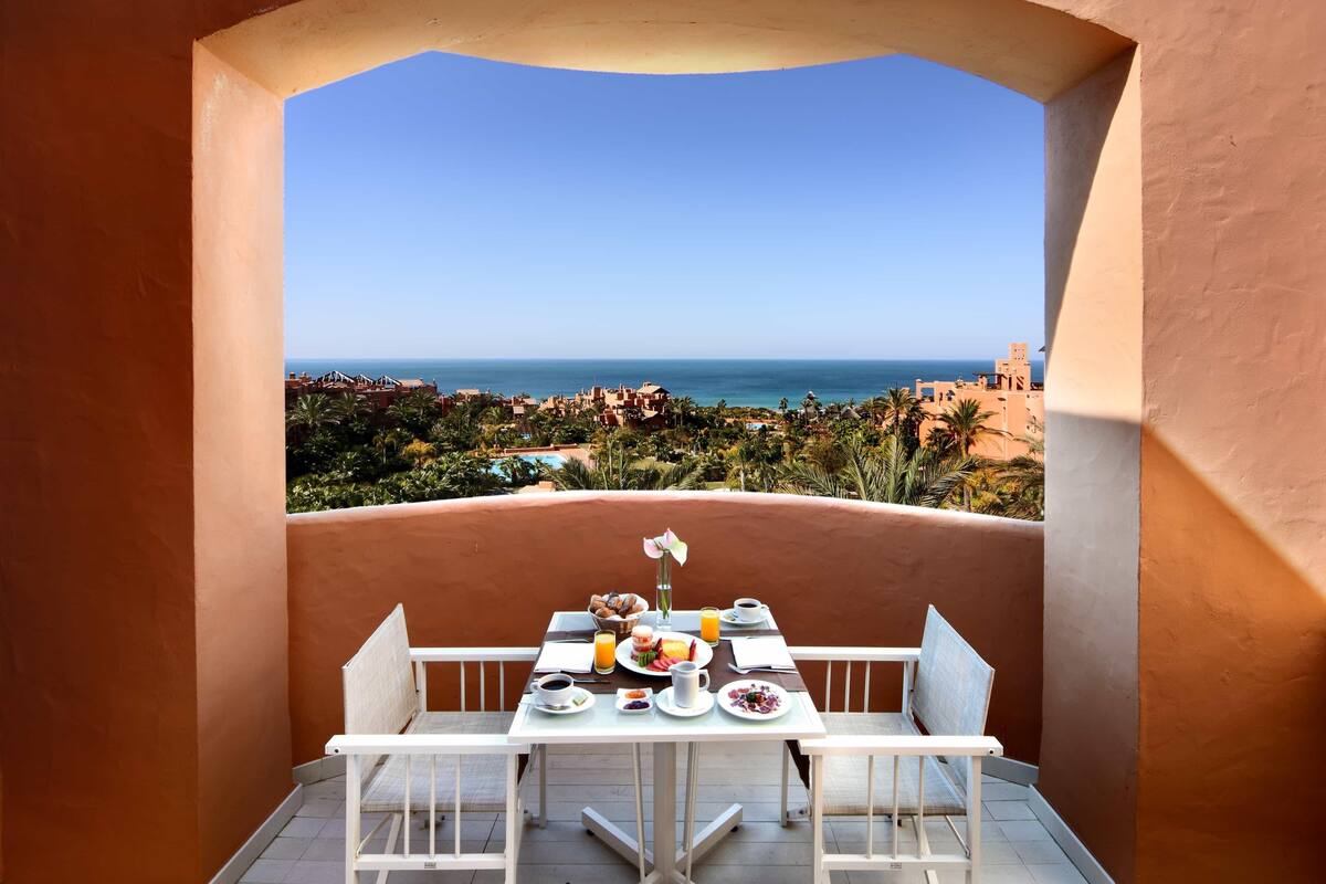 Un balcon avec une table préparée pour le petit-déjeuner, offrant une vue sur la côte.