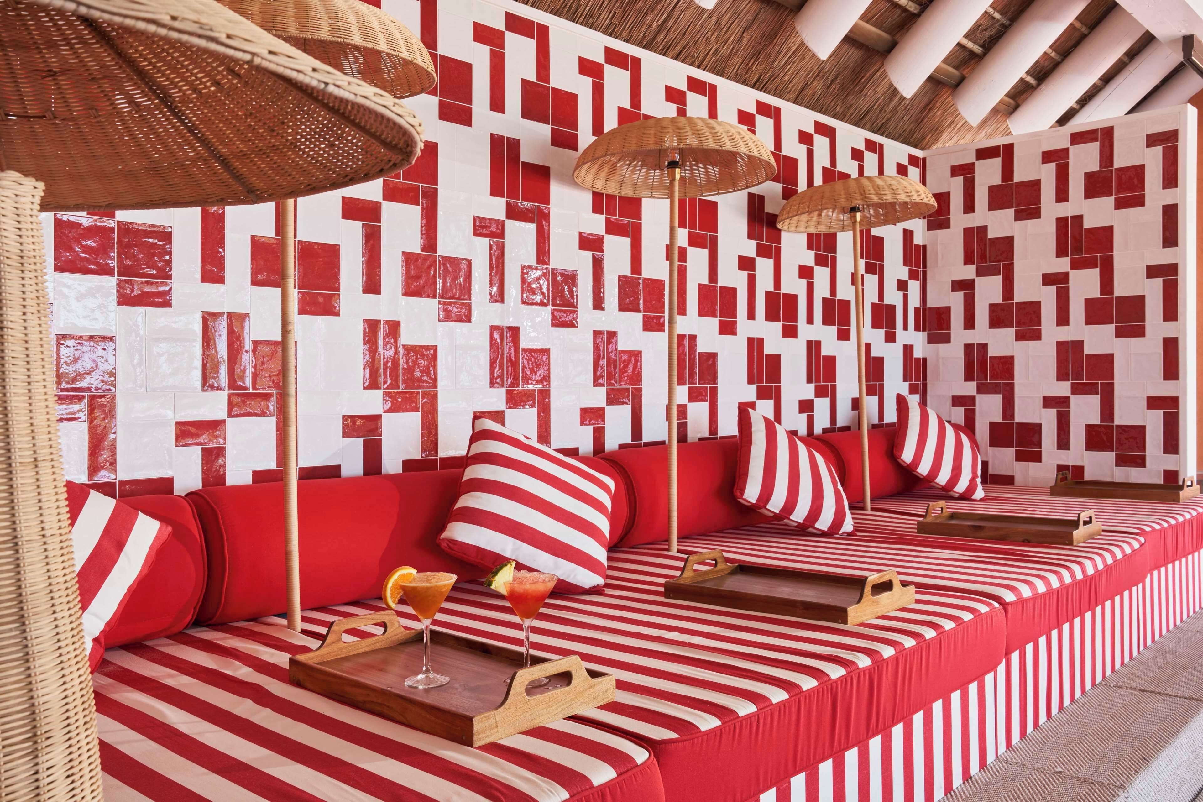A red and white striped sofa with cushions, a tray with drinks, and a patterned wall in the background.