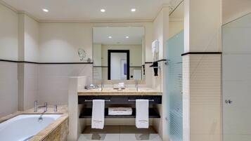 Un baño moderno con bañera, tocador doble y un espejo grande.