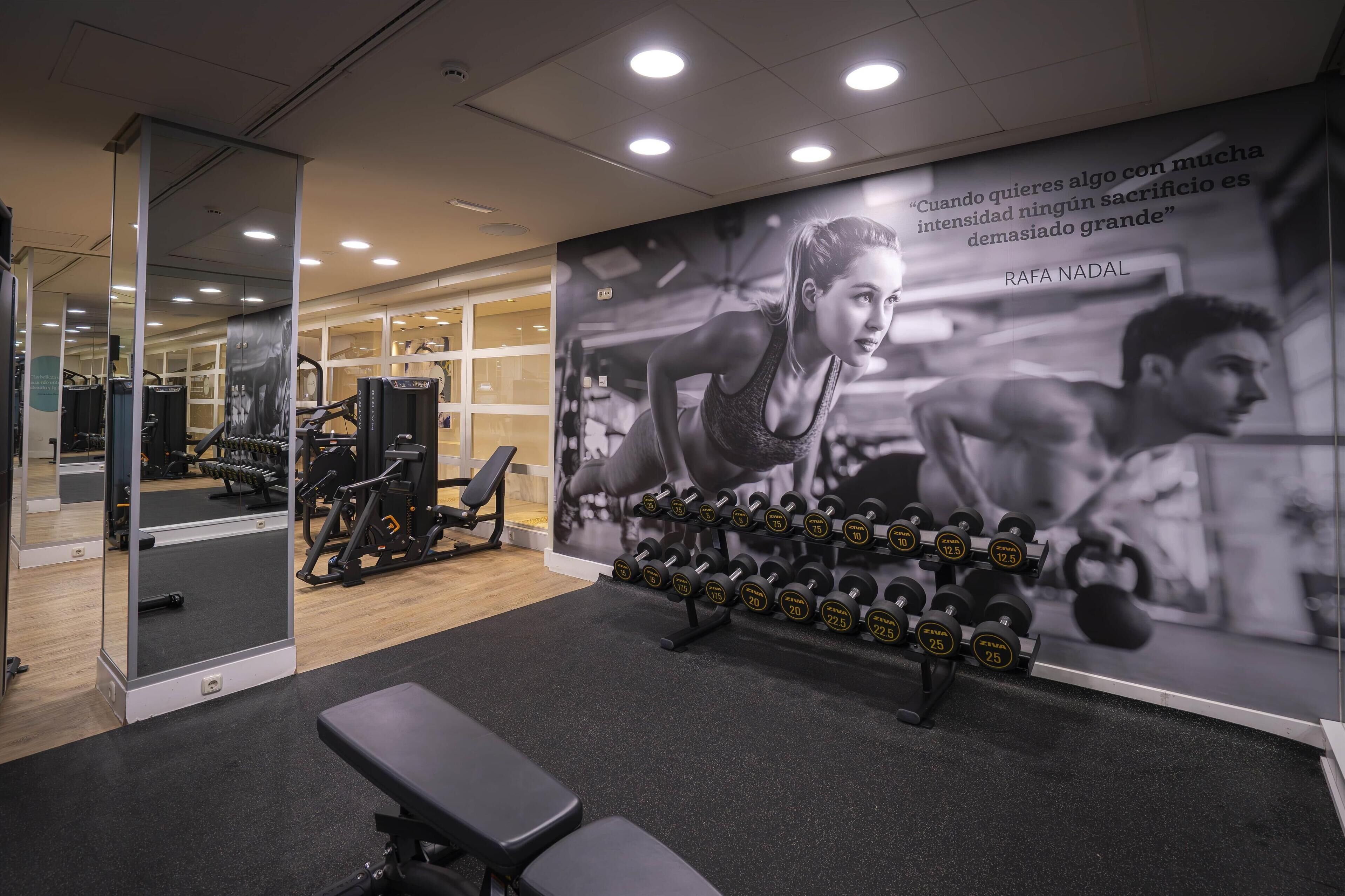 A gym with exercise equipment, a bench, and a motivational quote on the wall.