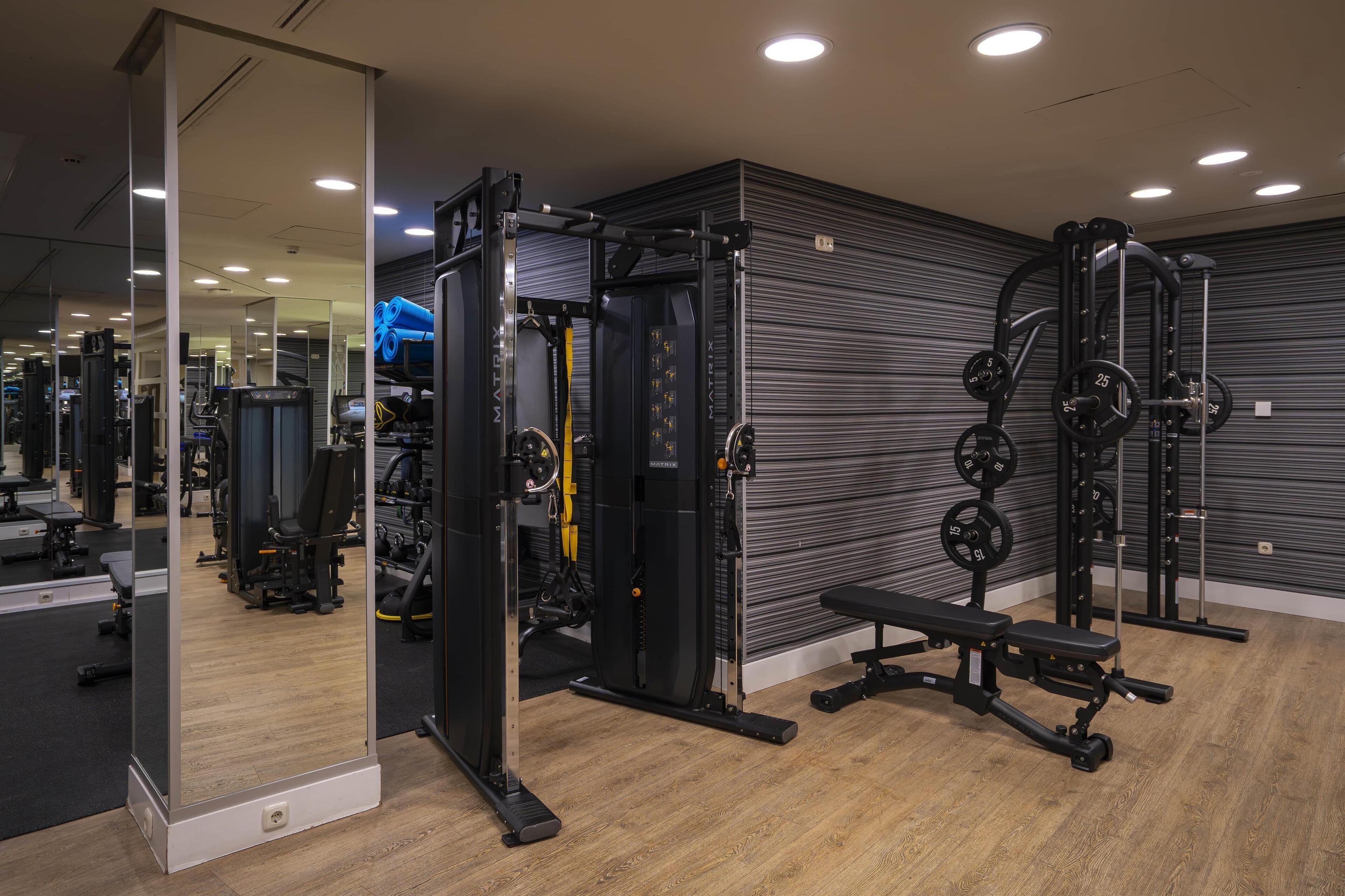 A gym with weightlifting equipment, a bench, and a mirror.