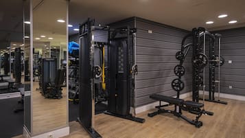 Un gimnasio con equipo de levantamiento de pesas, una banca y un espejo.