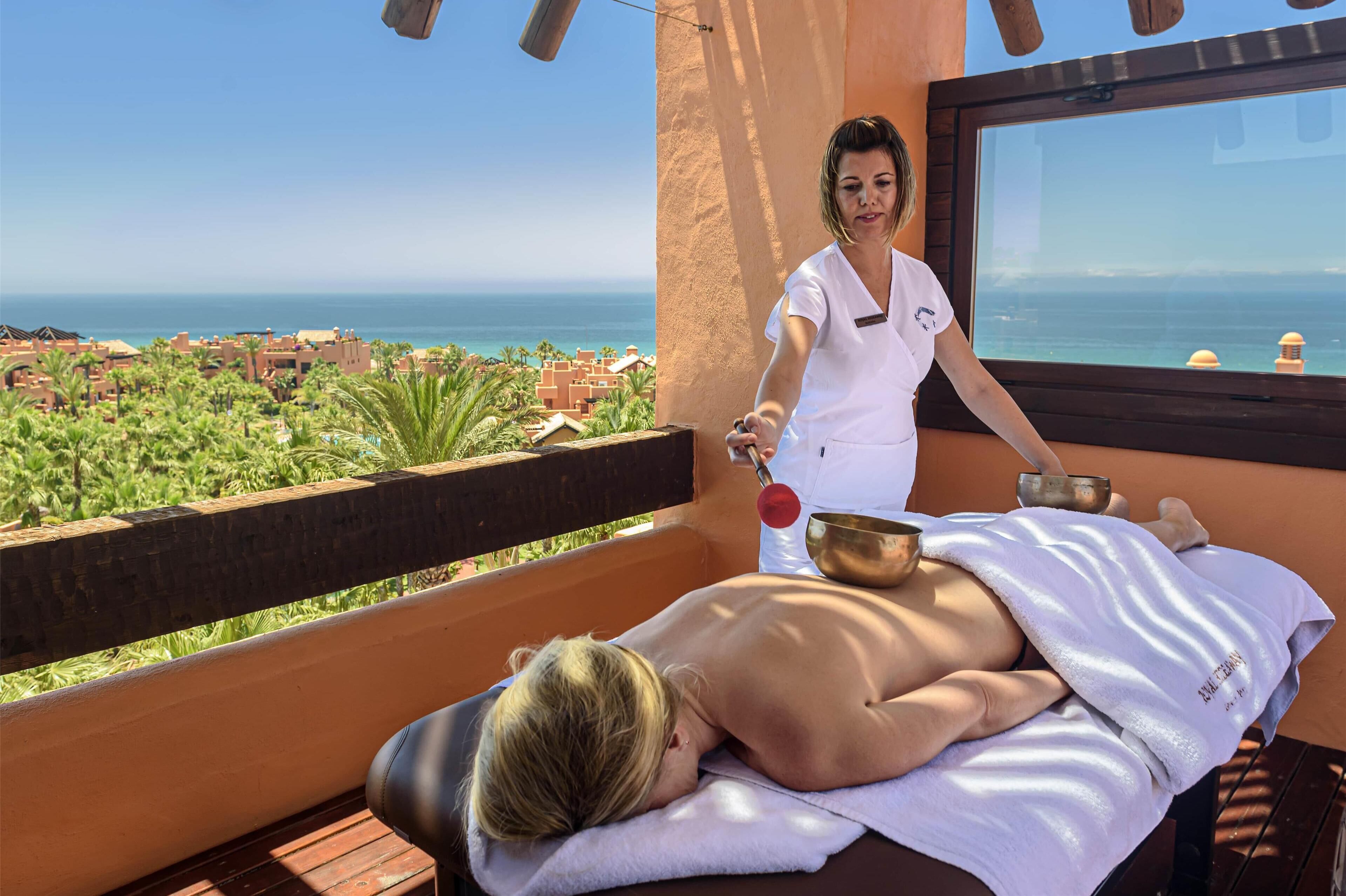 A massage therapy session on a balcony overlooking a coastal view.