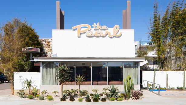 Un edificio con un letrero que dice "the Pearl" y un estilo arquitectónico moderno.