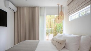 Un dormitorio moderno con cama, televisor montado en la pared y ventana con cortinas.