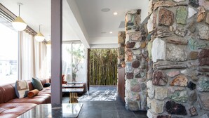Un interior moderno con pared de piedra, sofá de cuero e iluminación colgante.