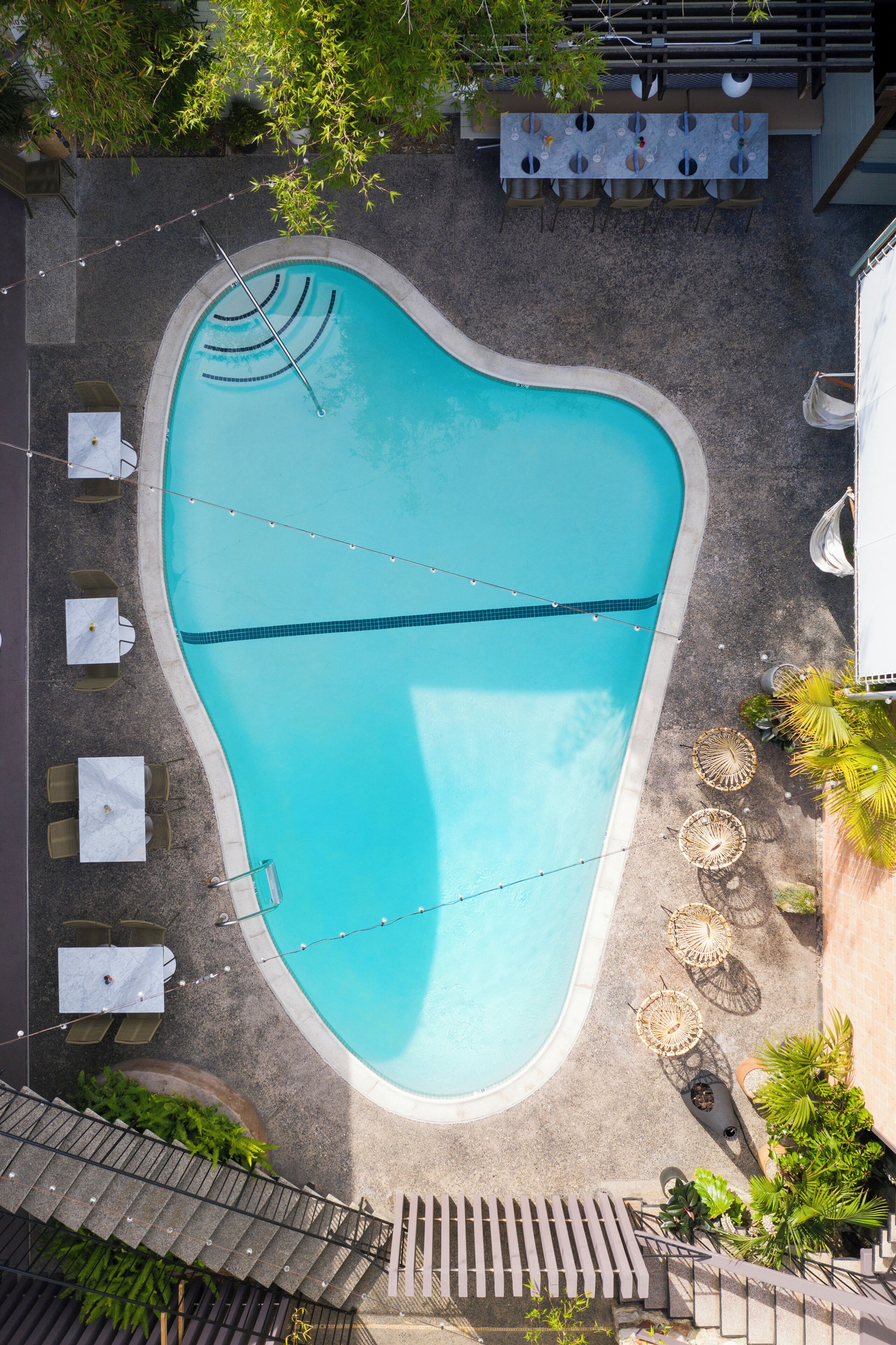 Eine Vogelperspektive auf einen Swimmingpool mit Liegestühlen, einem Tisch und einer Pergola.