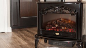 A cozy room with a wood-burning stove, a microwave, and a wooden cabinet. - The Landing at Morro Bay (Morro Bay)