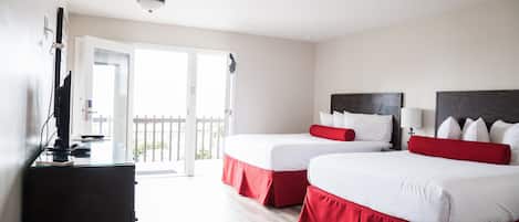 Een hotelkamer met twee bedden, een bureau en een schuifpui naar een balkon.
