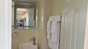 A bathroom with a white sink, a mirror, a towel rack, and a door.