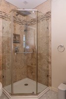 Une cabine de douche fermée par des parois en verre, équipée d’une barre d’appui, d’un pommeau de douche et d’un panneau de commande.