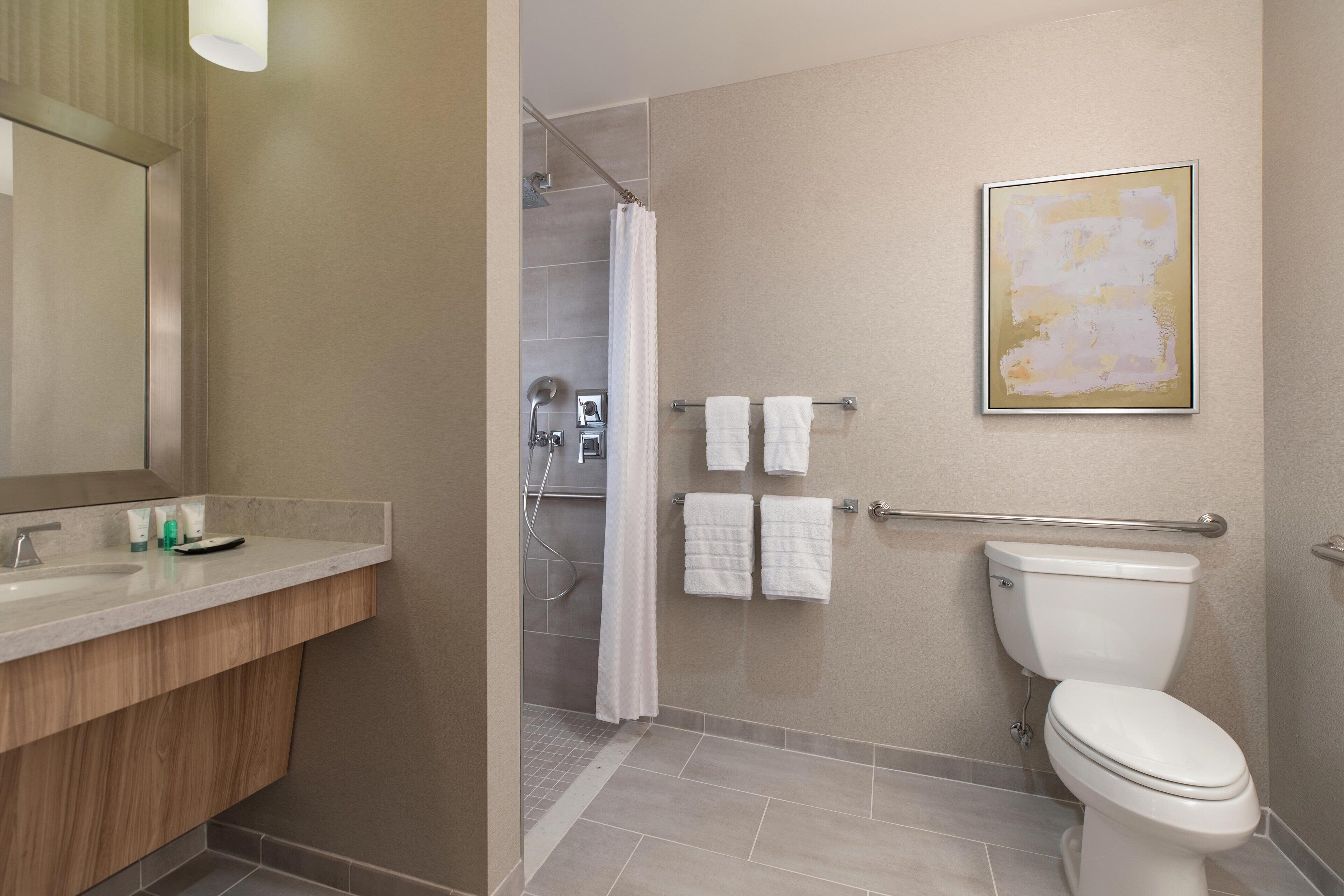 A modern bathroom with a shower, toilet, and vanity.