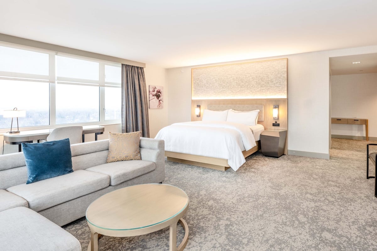 A hotel room with a bed, a sofa, a round table, and a desk.