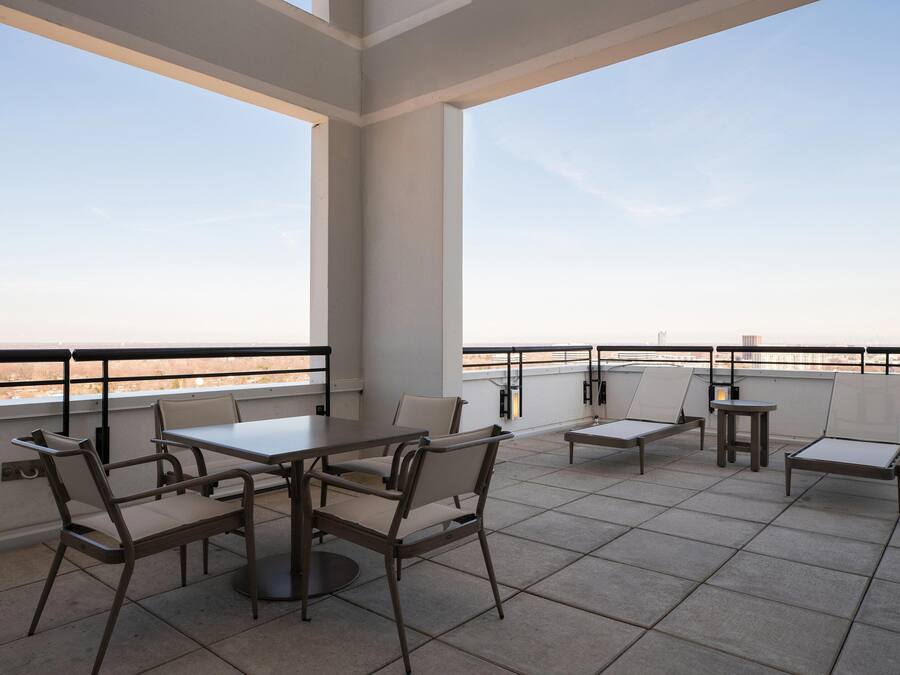 A rooftop terrace with a table and chairs, a small table, and a view of the city skyline.