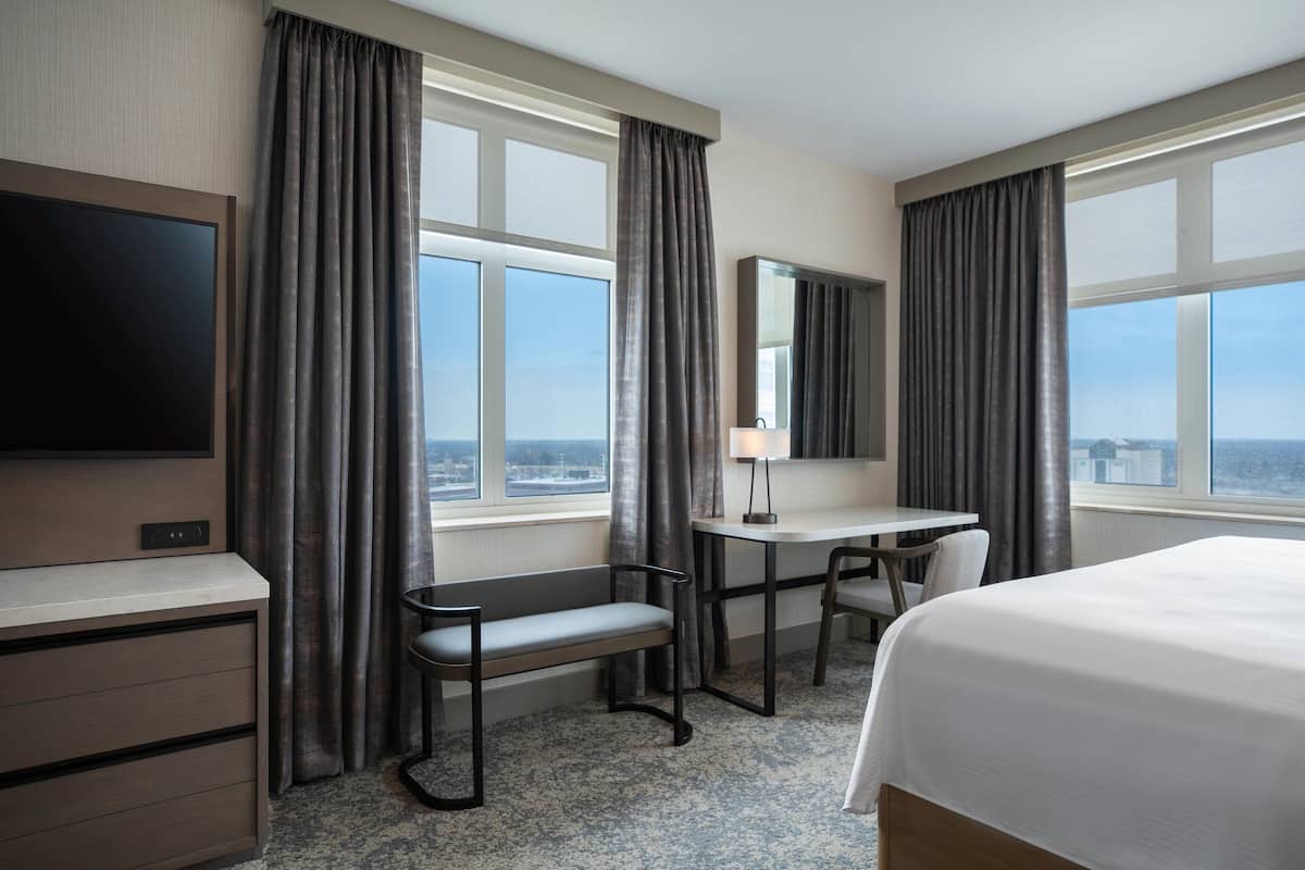 A hotel room with a bed, desk, chair, and TV.