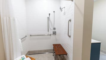 A wheelchair-accessible shower area with grab bars, a bench, and a towel rack.