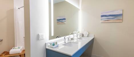 Une salle de bain moderne avec deux lavabos, un grand miroir et un banc en bois.