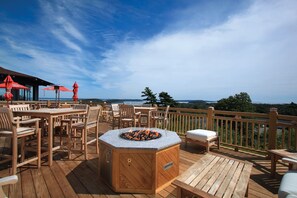 Une terrasse en bois avec des sièges extérieurs, un foyer et une vue sur l’océan.