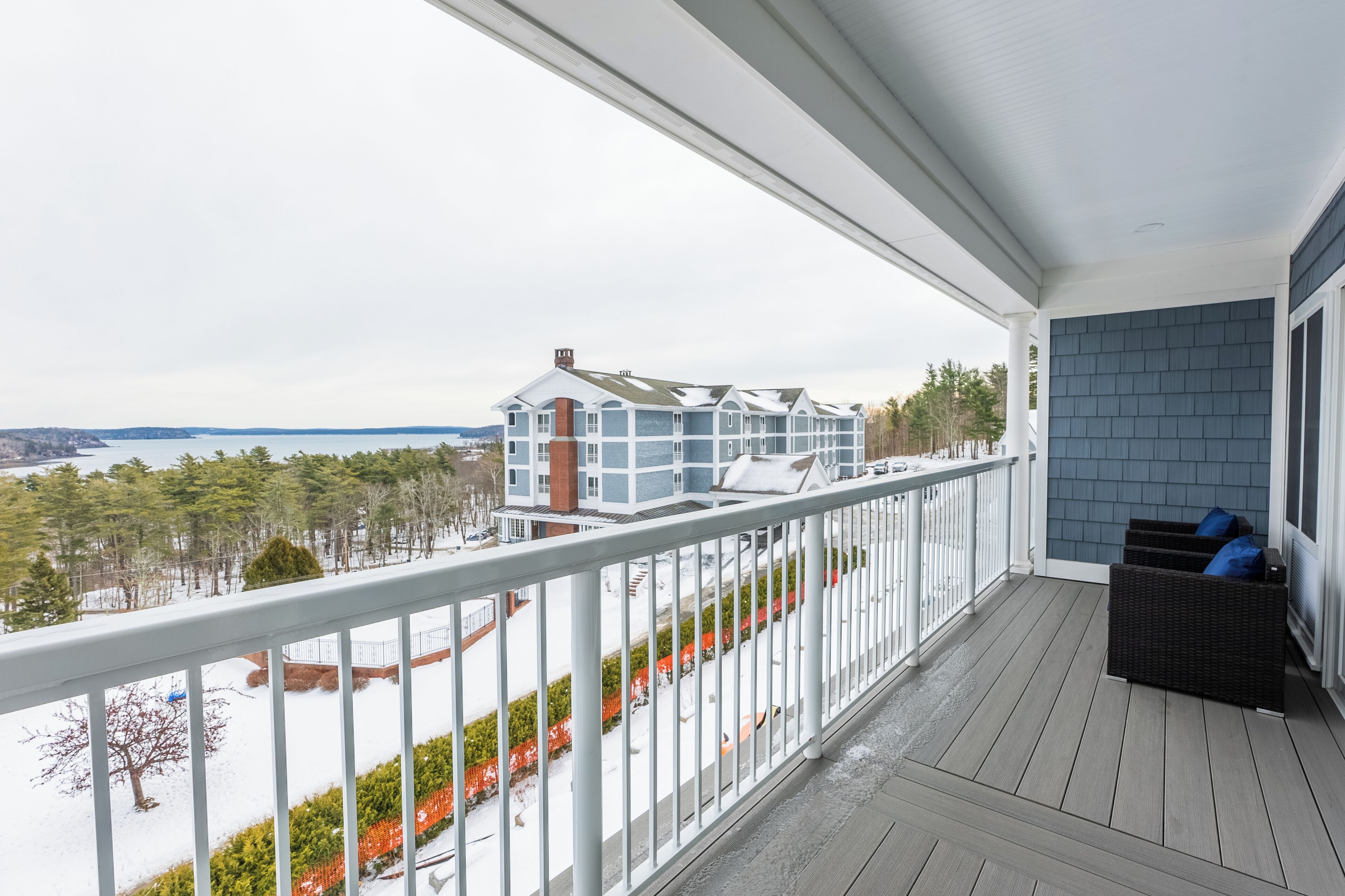 A covered balcony with a view of a building across a body of water.