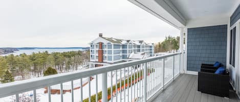 A covered balcony with a view of a building across a body of water.
