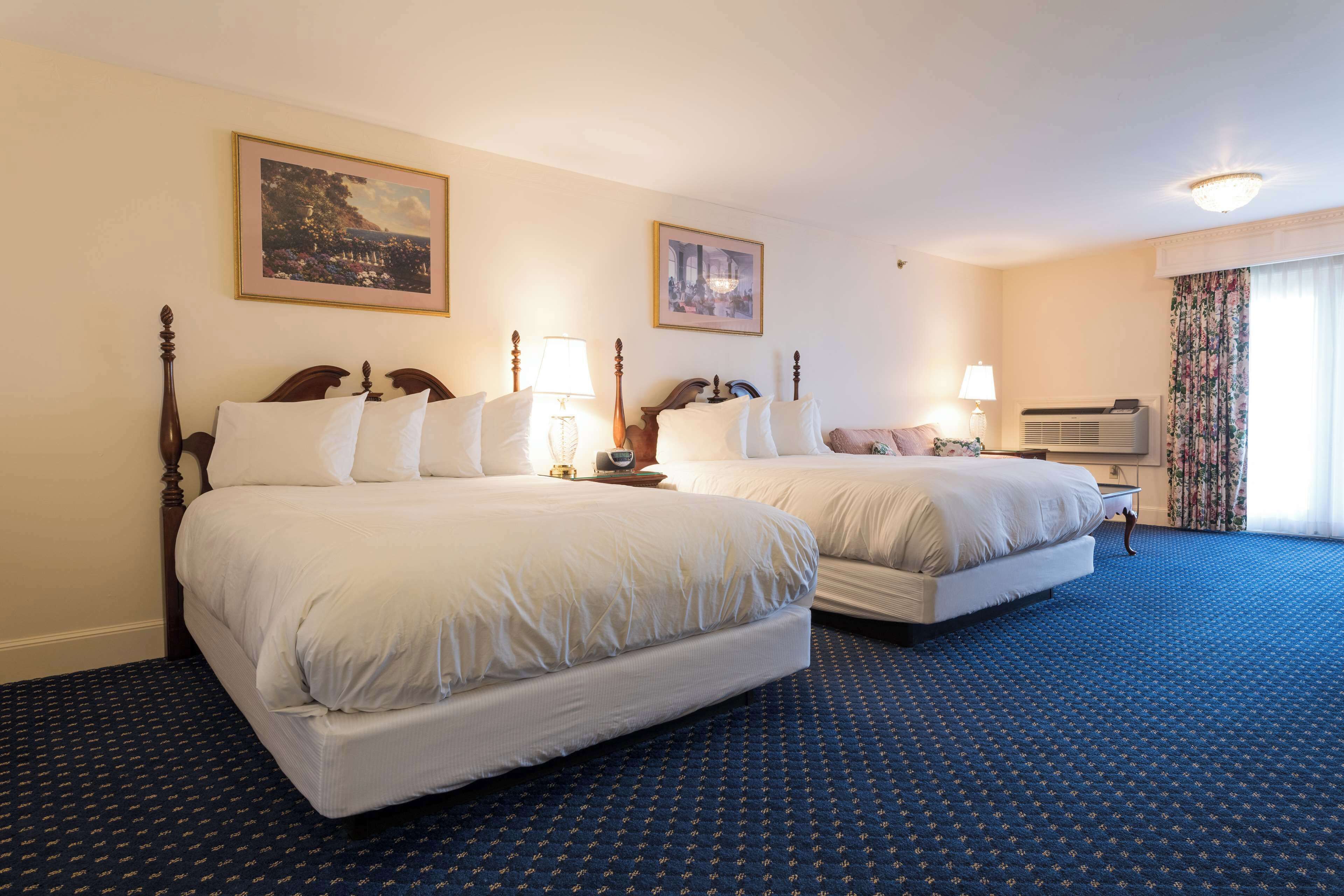 Une chambre d’hôtel avec deux lits, une télévision et une grande fenêtre avec des rideaux.