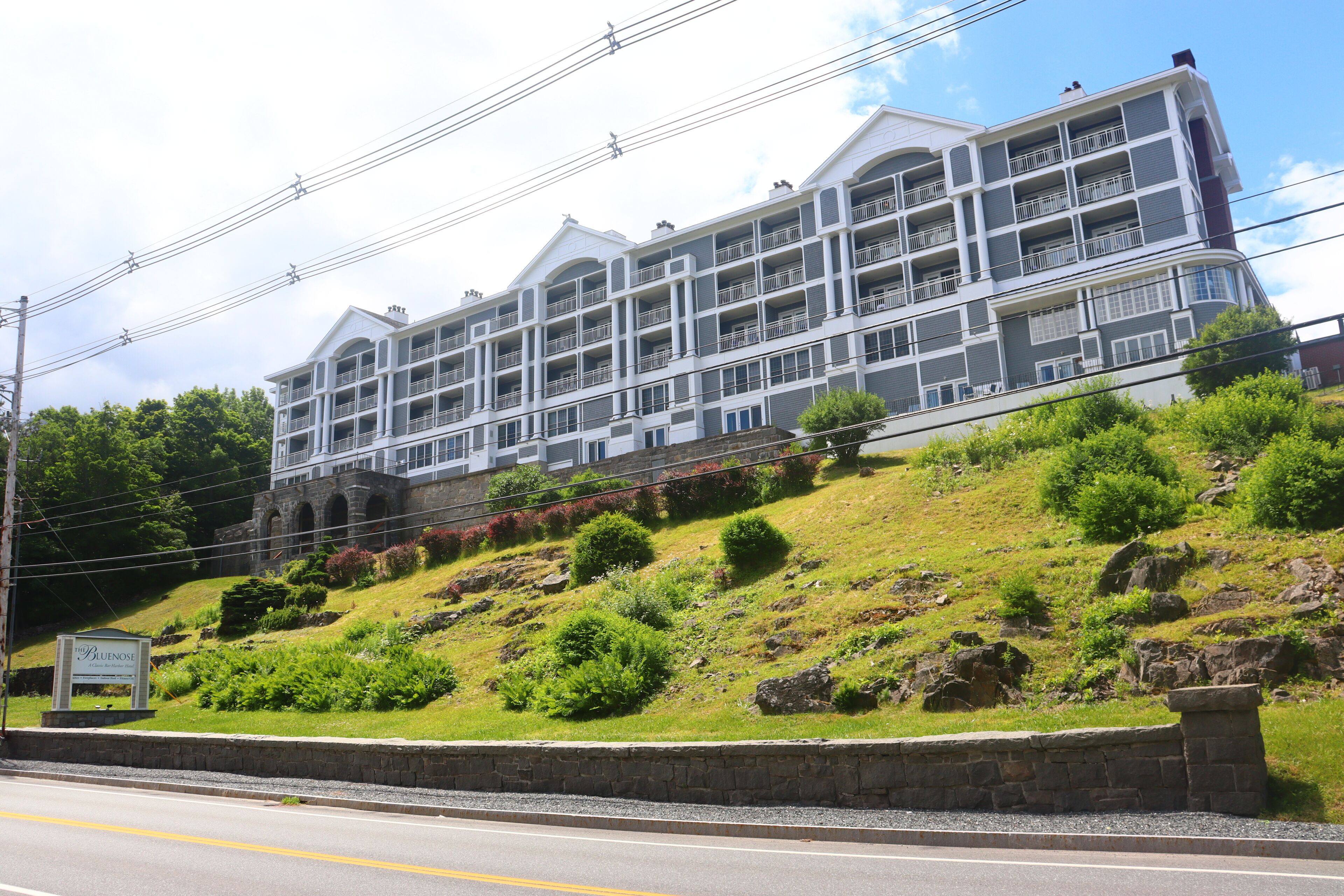 A multi-story hotel with balconies, situated on a grassy hillside.