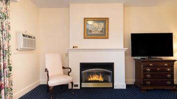 A room with a fireplace, a television, a chair, and a patterned carpet.