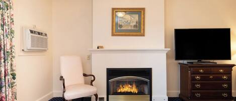 A room with a fireplace, a television, a chair, and a patterned carpet.
