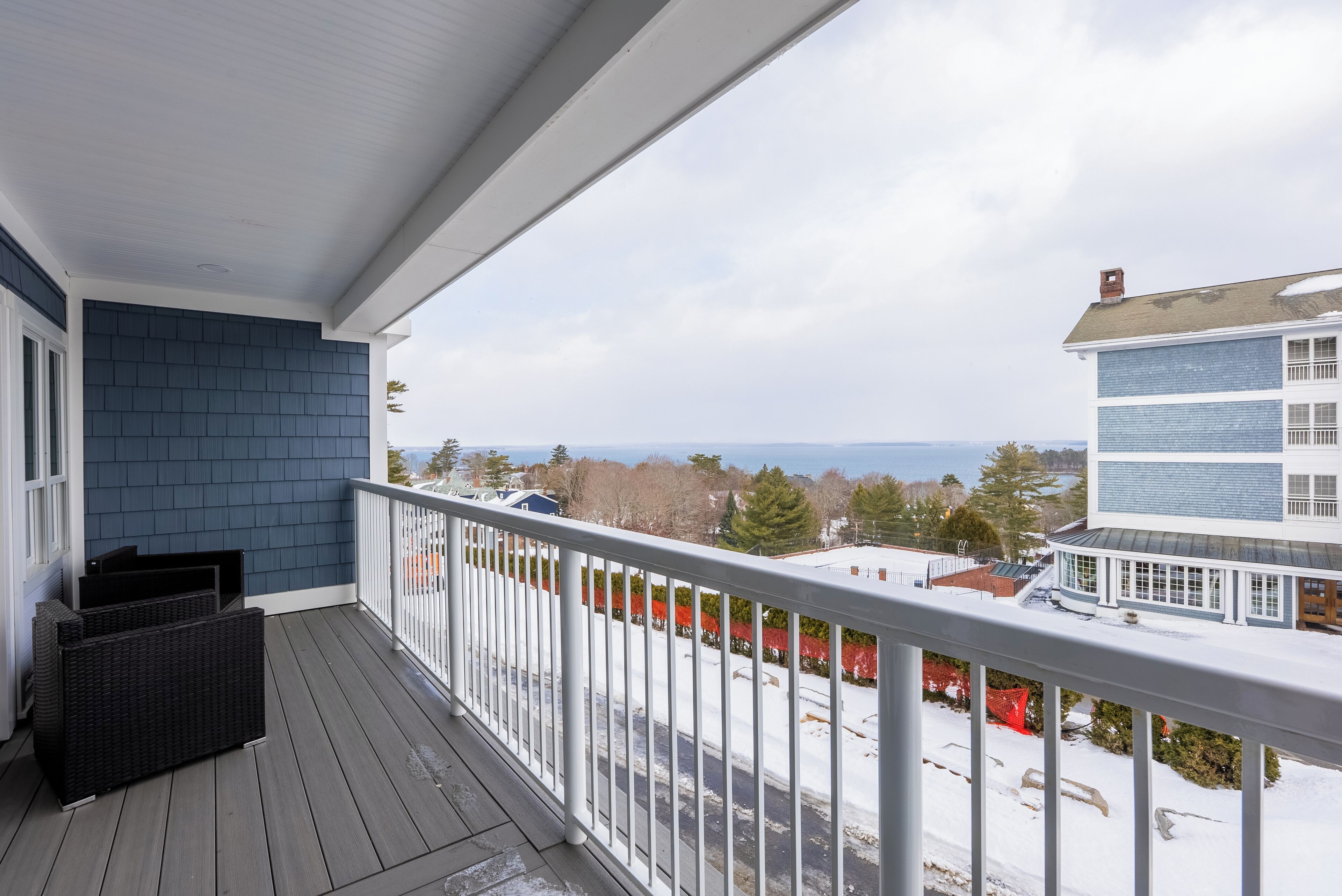 A balcony with a view of a snowy landscape and neighboring buildings.