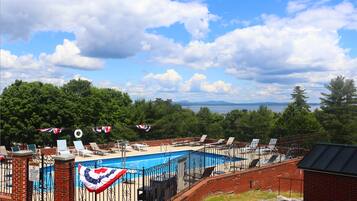 A swimming pool with lounge chairs and a flag decoration, surrounded by a brick wall and trees.