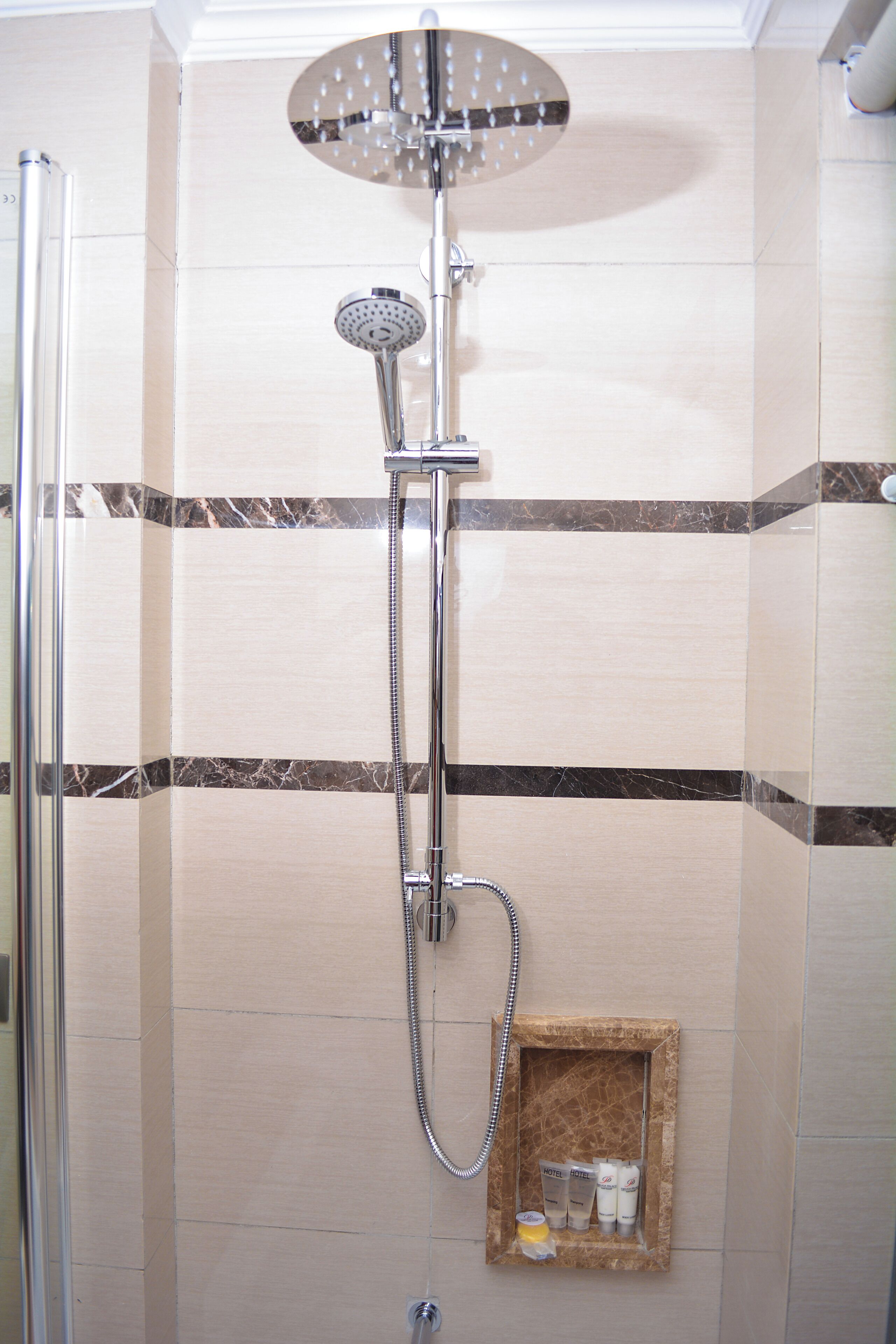 A shower with a handheld showerhead and a wall-mounted faucet.