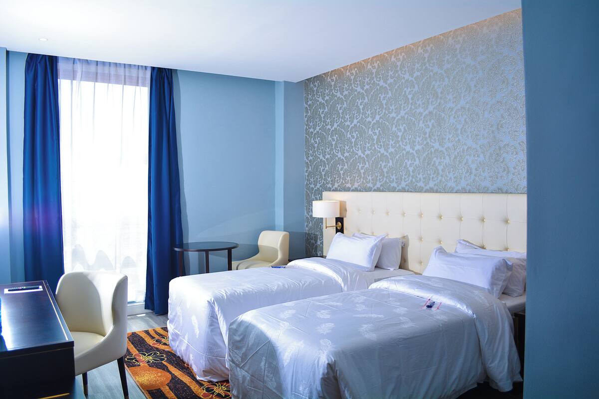 Una habitación de hotel con dos camas, un escritorio, una silla y una mesita.
