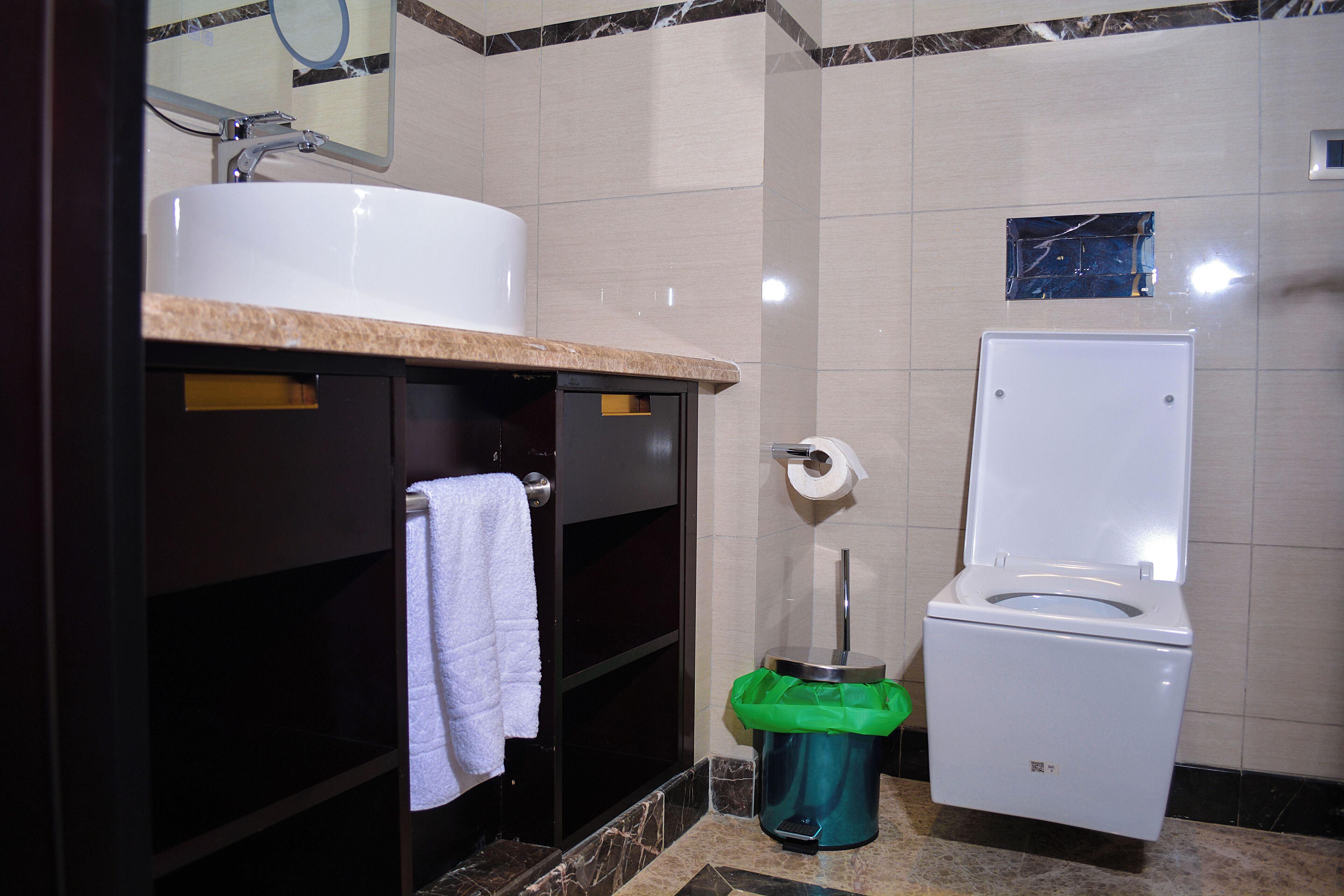 Un baño con lavamanos, inodoro y cubo de basura.