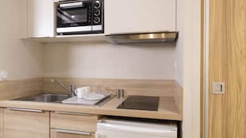 A modern kitchen with a built-in oven, stainless steel sink, and a compact refrigerator.
