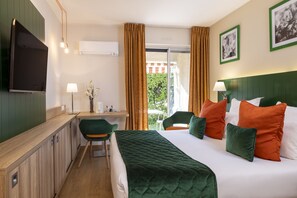 Une chambre d’hôtel avec un lit, un bureau, une chaise, une télévision et une fenêtre avec des rideaux.