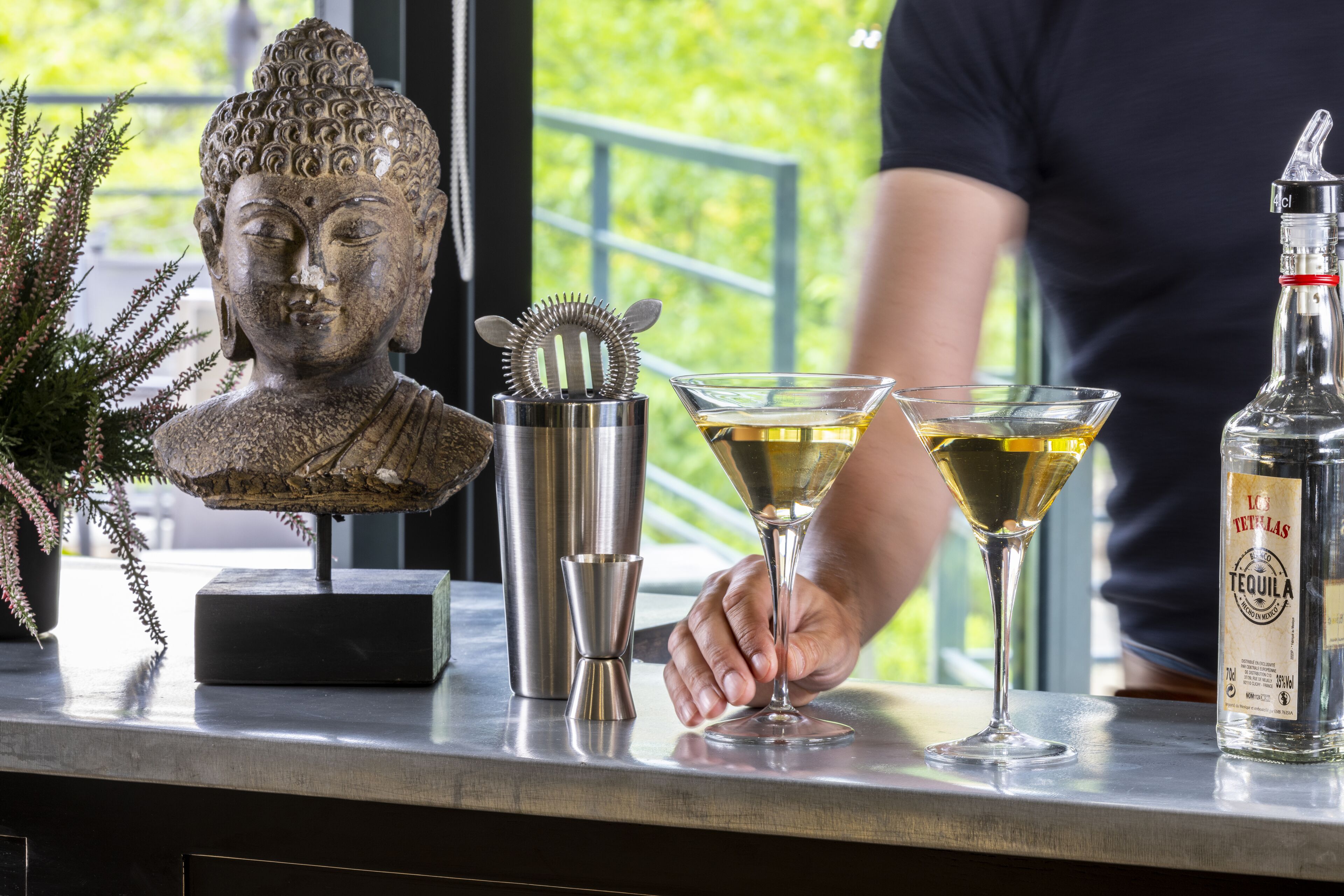 Zona de bar con una estatua de Buda, un mezclador de cócteles y una botella de tequila.