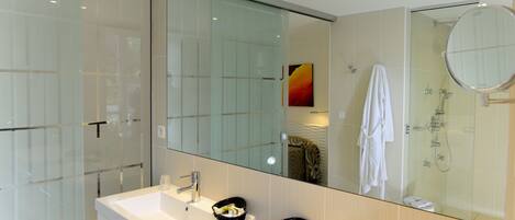 Une salle de bain moderne avec deux lavabos, une douche à l’italienne en verre et un grand miroir.