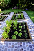 Un jardín con camas elevadas y un camino empavedado.