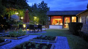 Une cour avec des sièges en plein air, un bâtiment en pierre et un jardin bien entretenu.