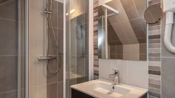 A modern bathroom with a glass-enclosed shower, a sink, and a vanity.