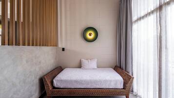 A room with a bed, a wall-mounted light, and a window with curtains.