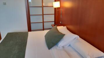 Una habitación de hotel con cama, mesita de noche, lámpara y puerta corredera.