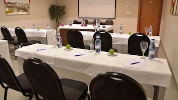 A conference room with tables set for meetings, equipped with water bottles, apples, and pens.