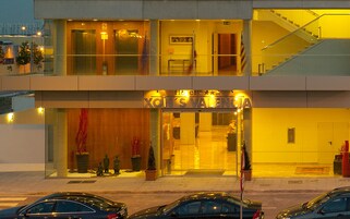 Entrada de hotel con puertas dobles, una escalera a la derecha y un cartel sobre las puertas.